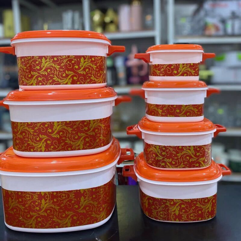 set-boites-conservation-orange-motif Lot de sept boîtes de conservation alimentaires de tailles différentes, blanches et oranges avec des motifs floraux dorés.