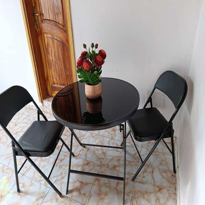 ensemble-table-chaises-pliantes-noir Ensemble de mobilier noir comprenant une table ronde à plateau brillant et deux chaises pliantes rembourrées.