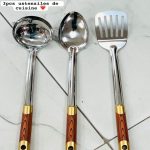 Lot de trois ustensiles de cuisine en inox comprenant une louche, une cuillère et une spatule avec manches aspect bois.