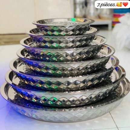 Pile de sept plateaux de service ronds en acier inoxydable avec bordures à motifs diamantés.