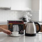 Bouilloire électrique en acier inoxydable Silver Love fumante sur un plan de travail avec une tasse de thé.