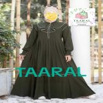 Femme portant une robe longue évasée de couleur vert kaki avec des détails de volants blancs sur le buste, un col montant zippé et des manches longues resserrées aux poignets, par Taaral Boutique.