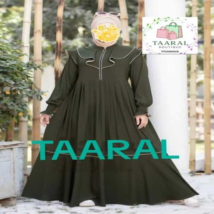 Femme portant une robe longue évasée de couleur vert kaki avec des détails de volants blancs sur le buste, un col montant zippé et des manches longues resserrées aux poignets, par Taaral Boutique.