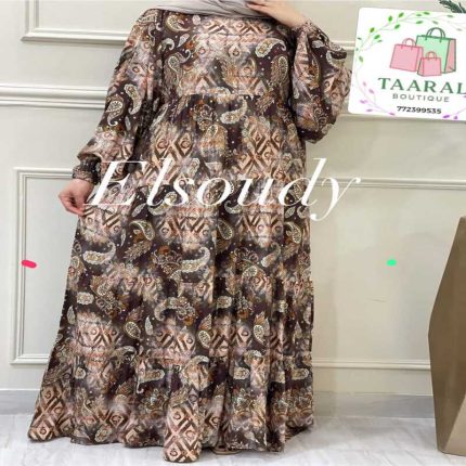 Femme portant une robe longue évasée à motifs imprimés de style ornemental et géométrique dans les tons vert, marron et beige, avec des manches longues bouffantes, par Taaral Boutique.