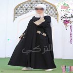 Femme portant une abaya moderne avec boutons sur le buste, revers de manches contrastés et grandes poches à l'avant.