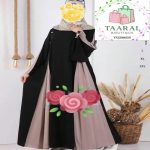 Femme portant une abaya longue bicolore avec des empiècements contrastés sur les côtés et des manches évasées épurées.