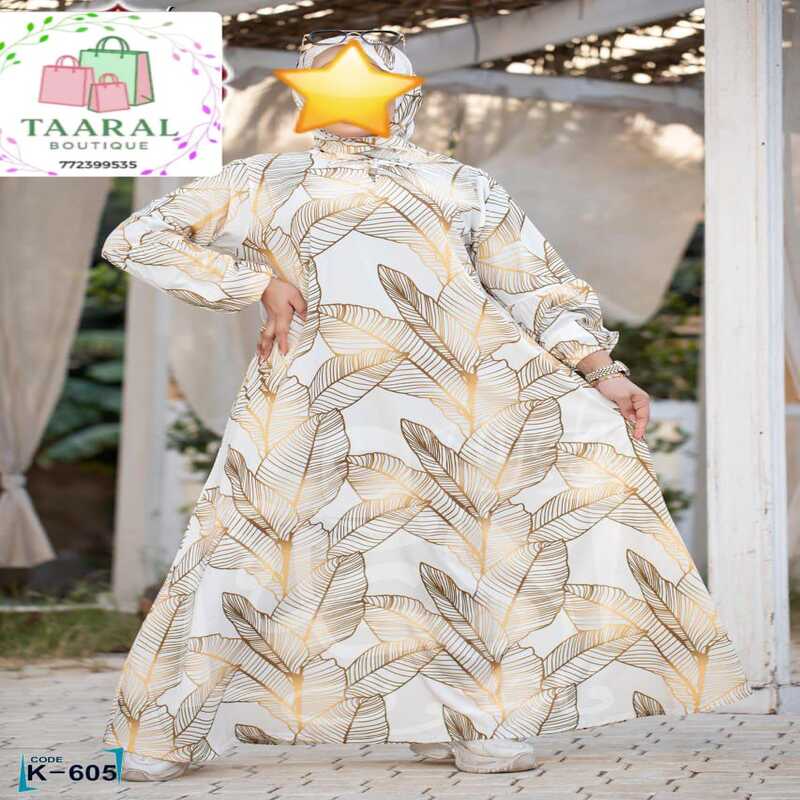 abaya-evasee-col-noue-taar-boutique Femme portant une longue abaya évasée à motifs avec un col à nouer et de volumineuses manches bouffantes.