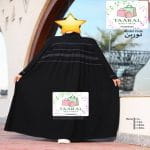 Femme portant une robe abaya longue et très ample, ornée de plis fins et de lignes horizontales contrastées sur le buste, de la boutique Taaral Boutique.