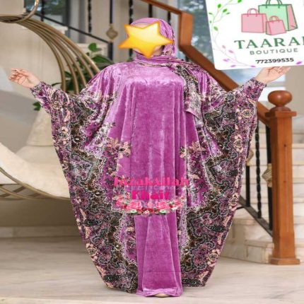 Femme portant une abaya papillon haut de gamme en tissu velours brillant avec des motifs orientaux ornementaux sur les côtés et un hijab assorti, de chez Taaral Boutique.