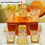 Lot de six verres à boisson transparents avec une finition et des reflets dorés brillants, dotés d'une forme évasée et d'une base géométrique texturée.