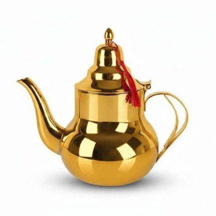 Théière marocaine traditionnelle en acier inoxydable doré brillant avec un pompon rouge suspendu au couvercle, isolée sur fond blanc.