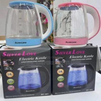 Deux bouilloires électriques en verre transparent de marque Silver Love, l'une bleue et l'autre rose, posées sur leurs boîtes d'emballage respectives.
