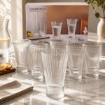 Lot de six grands verres à eau transparents au design strié vertical et base resserrée, disposés sur une table en marbre lumineuse devant leur boîte de la marque Diamonds.