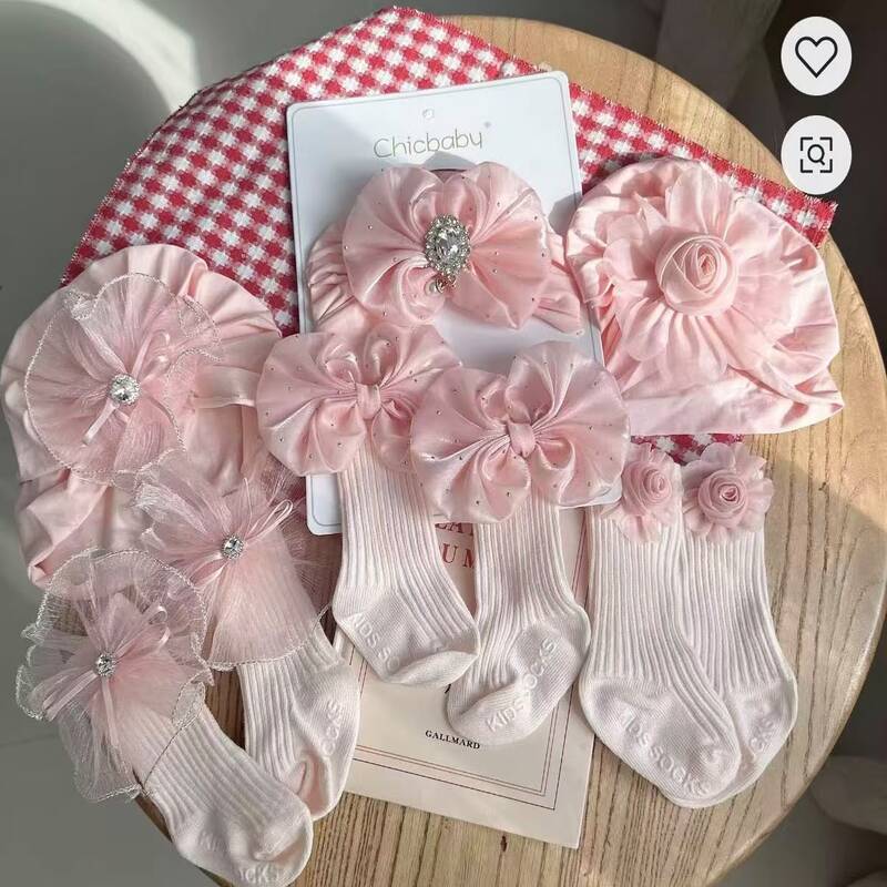 coffret-bonnet-turban-chaussettes-bebe Coffret d'accessoires pour bébé de la marque Chicbaby présenté sur un support en bois, comprenant un bonnet de style turban orné d'un grand nœud strassé et une paire de chaussettes hautes assorties avec des nœuds décoratifs.