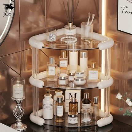 Organisateur d'angle à trois niveaux avec plateaux transparents, installé sur un plan de travail et rempli de flacons de parfum, de crèmes de soin et d'accessoires de beauté.