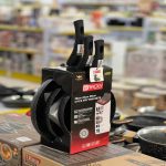 Emballage cartonné contenant un lot de trois poêles de tailles différentes empilées verticalement avec leurs manches visibles, posé sur une étagère de magasin.