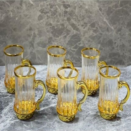 Un ensemble de six tasses en verre transparent aux parois finement ciselées, dotées d'une anse courbée et de finitions brillantes sur le col et la base, disposées sur une surface marbrée.