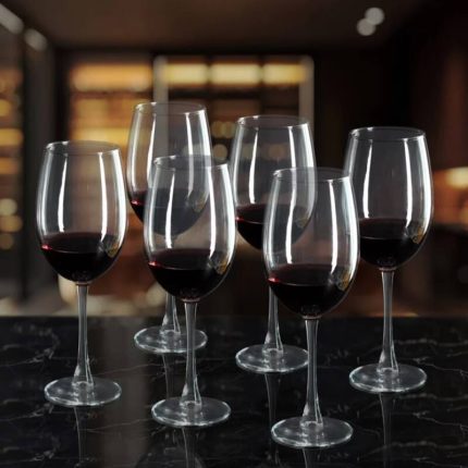 Service de six verres à pied transparents de forme élégante et arrondie alignés sur une table.