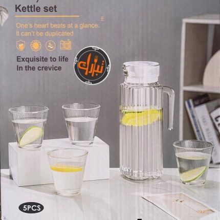 Carafe haute en verre transparent remplie d'eau et de tranches de citron, accompagnée de quatre verres assortis disposés sur une table claire dans un intérieur moderne.