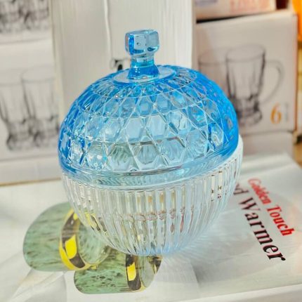 Petit pot décoratif en verre transparent bleu turquoise avec des reliefs losanges ciselés et un couvercle pointu assorti.