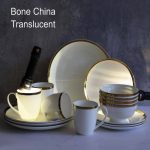 Collection de vaisselle de luxe en porcelaine blanche éclatante comprenant des assiettes de différentes tailles et des tasses, toutes finies par un liseré doré brillant sur les bords.