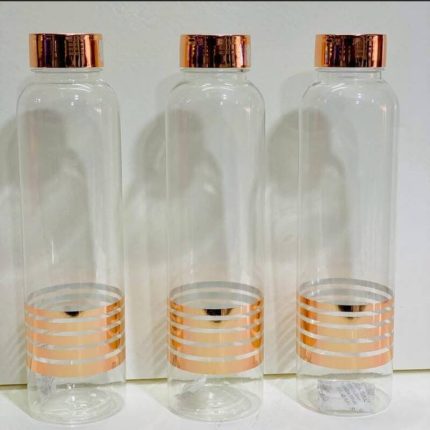 Trois bouteilles cylindriques en verre transparent alignées, décorées de trois bandes horizontales or rose à leur base et équipées de bouchons métalliques assortis.