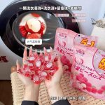 Sachets de capsules de lessive 5-en-1 Gelijing parfumées avec des perles de gel roses étalées sur une table.