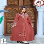 Jeune fille portant une longue abaya ou djellaba égyptienne marron brique avec des ornements de strass dorés devant de grandes portes en bois sculpté.