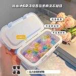 Boîte en plastique blanc ouverte contenant des capsules de lessive 6D multicolores en forme de perles de gel pour la protection des couleurs.