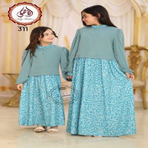 Deux jeunes filles portant une longue robe égyptienne bleu turquoise en soie et crêpe avec un haut uni à manches longues et une jupe à motifs abstraits.